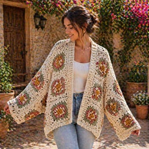 May include: Cream-colored crochet cardigan with square floral patterns in shades of pink, green, and yellow. The open-front sweater has long sleeves and a relaxed fit, perfect for layering. The cardigan is made of a soft, textured yarn.