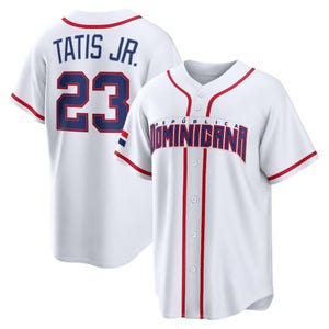 Puede incluir: Camiseta de béisbol blanca con ribetes rojos y letras azules. La camiseta lleva "TATIS JR. 23" en la espalda y "REPÚBLICA DOMINICANA" en la parte delantera. La camiseta tiene botones y mangas cortas.