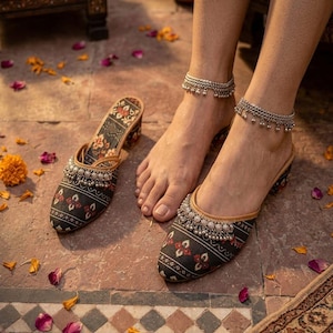 Puede incluir: Un par de zapatos sin cordones con estampado negro y rojo con adornos plateados. Los zapatos se muestran con un par de tobilleras plateadas a juego. Los zapatos tienen un tac&oacute;n peque&ntilde;o y est&aacute;n decorados con motivos florales.