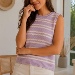 May include: A sleeveless, lilac-colored sweater vest with horizontal cream-colored stripes. The knitwear has a round neckline and a ribbed hem. The vest is made of a soft, lightweight material, perfect for layering or wearing on its own.