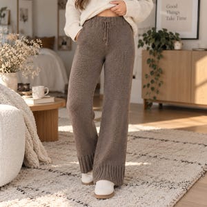 Op de afbeelding: Gebreide broek met hoge taille in een effen taupe kleur, voorzien van een wijd uitlopend model, een geribbelde elastische tailleband met een functioneel trekkoord en brede geribbelde boorden aan de zoom. Gemaakt van zachte, gebreide stof.