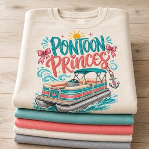 Op de afbeelding: Een stapel opgevouwen sweatshirts in crème, blauwgroen, koraal en grijs. Het bovenste sweatshirt heeft een afbeelding van een pontonboot met de woorden "Pontoon Princess" in blauwgroen en koraal, met zon- en strikaccenten.