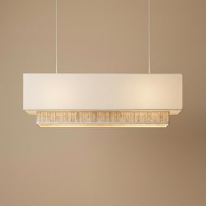 May include: A rectangular pendant light fixture featuring a large, solid off-white fabric shade layered over a smaller, textured beige woven trim. The fixture is suspended by two thin, vertical wires, emitting a soft, warm glow from the bottom.