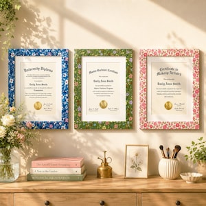 May include: Three rectangular picture frames with floral patterns in blue, green, and pink. Each frame holds a document: a University Diploma, a Master Gardener Certificate, and a Certificate in Makeup Artistry, all featuring the name Emily Anne Smith.