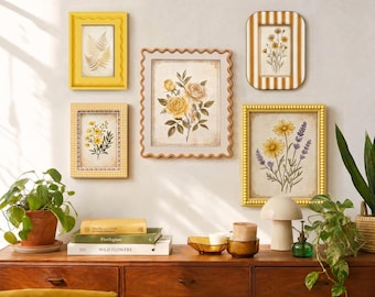 May include: A gallery wall arrangement featuring five framed botanical prints with yellow and white accents. The central print displays yellow roses, surrounded by smaller frames containing ferns, daisies, and lavender illustrations. The frames vary in texture and color, including solid yellow, checkered, and striped patterns, displayed above a wooden sideboard.