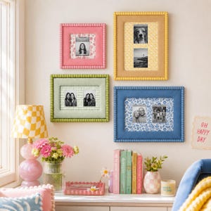 May include: A collection of four rectangular wall-mounted picture frames in pink, yellow, light green, and blue, each featuring a beaded border. The frames contain various black and white photographs set against patterned backgrounds of floral and geometric prints.