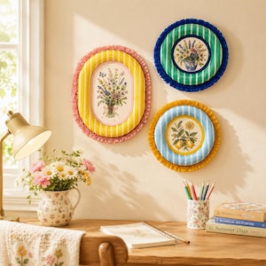 May include: Three decorative wall plaques featuring floral illustrations. One large oval plaque with yellow stripes and pink ruffles, and two circular plaques with green or blue stripes and ruffled edges, displaying bouquets of flowers and lemons.