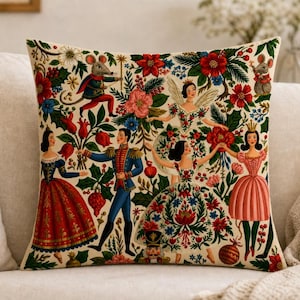 May include: A square throw pillow featuring a cream-colored background with a colorful illustration of characters from The Nutcracker, including a soldier, dancers, and mice, surrounded by red poinsettias, green foliage, and floral patterns.