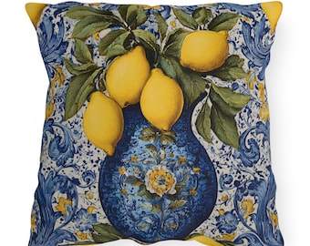 May include: A square throw pillow featuring a vibrant print of bright yellow lemons with green leaves arranged in a dark blue decorative vase. The background displays an intricate blue and white floral pattern with swirling acanthus leaf motifs.