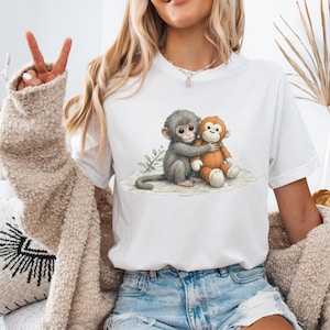 May include: White t-shirt with a watercolour illustration of two monkeys embracing. One monkey is grey, the other is orange. The design is printed on a white t-shirt.