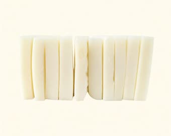 May include: A close-up shot of a stack of white, rectangular food items. The items are arranged vertically, side by side, creating a textured surface. The food items appear to be a type of rice cake or similar food product.