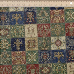 Puede incluir: Primer plano de una tela con diseño de patchwork. Los cuadrados presentan patrones simétricos ornamentados en tonos verdes, azules, rojos y beige. Una regla es visible en la parte superior, indicando medidas.