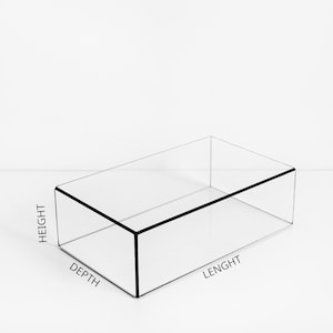 Könnte beinhalten: Eine transparente, rechteckige Vitrine mit schwarzem Rand. Die Box ist transparent und ermöglicht volle Sichtbarkeit des Inhalts. Die Abmessungen sind als Höhe, Tiefe und Länge gekennzeichnet. Ideal für die Präsentation von Produkten.