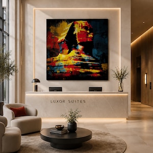 May include: A square wall art piece featuring a vibrant, abstract painting of the Great Sphinx of Giza in bold red, yellow, and blue tones. The artwork is mounted on a light-coloured wall above a reception desk labelled LUXOR SUITES.