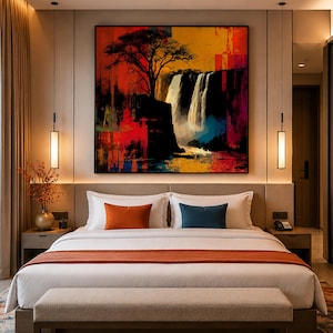 Op de afbeelding: Een slaapkamer met een groot vierkant kunstwerk aan de muur met een silhouet van een boom boven een waterval in levendige abstracte kleuren zoals rood, oranje en blauw. Het bed heeft wit beddengoed, een oranje loper en twee sierkussens.