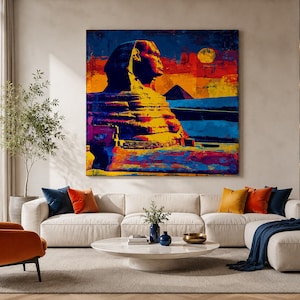 May include: A large square wall art print featuring a vibrant, multi-coloured artistic depiction of the Great Sphinx of Giza. The artwork uses bold shades of blue, orange, yellow, and purple to portray the monument against a desert landscape.