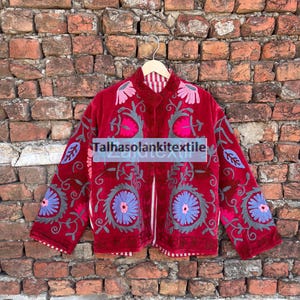 Könnte beinhalten: Rote Samtjacke mit floralen Stickereien in Rosa, Blau und Grau. Die Jacke hat lange Ärmel und ein gestreiftes Futter. Der Text "Talhasolankitextile" ist sichtbar.