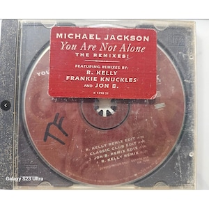 May include: A CD of Michael Jackson's "You Are Not Alone: The Remixes!" featuring remixes by R. Kelly, Frankie Knuckles, and Jon B. The CD is in a clear plastic case with a red sticker. The CD has the text "TF" on it.