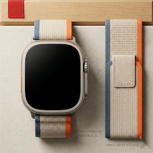 Puede incluir: Un reloj inteligente plateado con una pantalla negra y una correa de tela beige, azul y naranja. La correa está separada y se muestra junto al reloj. El texto en la imagen dice "ULTRA-PREMIUM MATERIALS" y "HAND-CRAFTED WID".