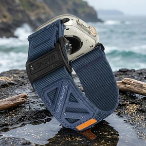 May include: A silver smartwatch with a navy blue nylon band. The band features a black magnetic clasp and a blue patch with the text "Extreme Sports". An orange accent is visible on the band. The watch is water resistant.