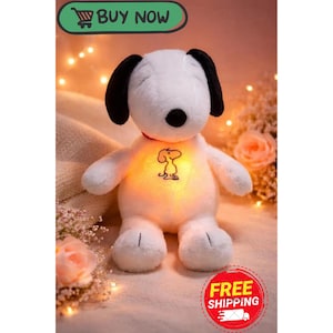May include: A plush white Snoopy stuffed animal with black ears, a black nose, and a red collar. The Snoopy toy has a glowing belly with a Snoopy graphic. The image includes the text "BUY NOW" and "FREE SHIPPING".