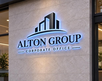 以下が含まれることがあります： 青いバックライトで照らされた黒い文字で「ALTON GROUP CORPORATE OFFICE」と書かれた立体的な壁面看板。テキストの上には、建物のシルエットと曲線を描いた黒いグラフィックが配置されています。