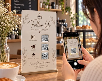 以下が含まれることがあります： 金色のベースが付いた長方形の白いアクリル看板。Follow Us On Social Media、Instagram、TikTok、Google Reviewのアイコンと3つのQRコード、およびLeave Us a ReviewとYour Support Means a Lotというテキストが記載されています。