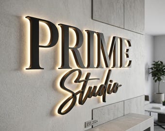 Op de afbeelding: Een wandbord met de zwarte tekst PRIME Studio met achtergrondverlichting die een gloeiend halo-effect creëert. Onder de hoofdtekst toont een klein rechthoekig plaatje de tekst EST. 2024 in een strak, schreefloos lettertype.