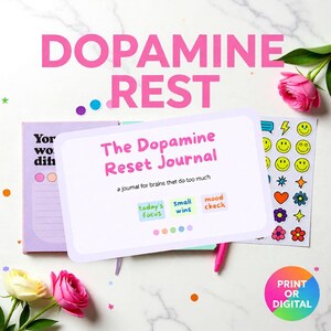 May include: An open journal titled "The Dopamine Reset Journal" with the text "a journal for brains that do too much." Stickers and flowers are placed nearby. The words "DOPAMINE REST" are in large pink letters above the journal.