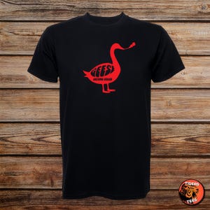 May include: Black t-shirt featuring a red goose graphic with the word "GEESE" inside the goose shape and the words "GETTING KILLED" below. The shirt is made of a soft material.