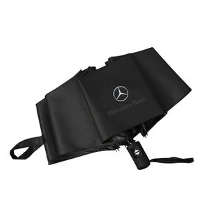 May include: Black, compact, folding umbrella with the Mercedes-Benz logo and text. The umbrella is partially open, revealing its interior structure. It has a black handle with a button and a wrist strap.
