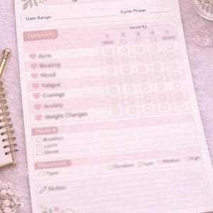 May include: A pink symptom tracker with the text "Symptom Tracker". It features sections for date range, cycle phase, and symptom severity. Floral decorations and a spiral notebook are also visible.