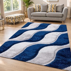 May include: A rectangular area rug featuring a high-pile texture with a repeating pattern of thick, wavy bands in alternating shades of deep navy blue and light silver grey, creating a soft, dimensional surface across the entire floor covering.