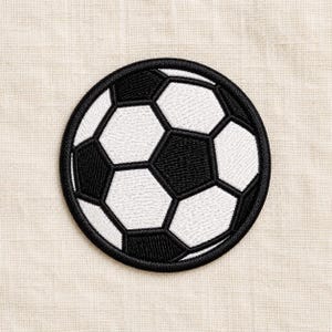 Könnte beinhalten: Ein kreisförmiger, bestickter Aufnäher mit einem klassischen Fußballmotiv. Der Aufnäher besteht aus abwechselnd schwarzen und weißen sechseckigen und fünfeckigen Formen und ist mit einem dicken, schwarzen Stickrand am Außenrand versehen.