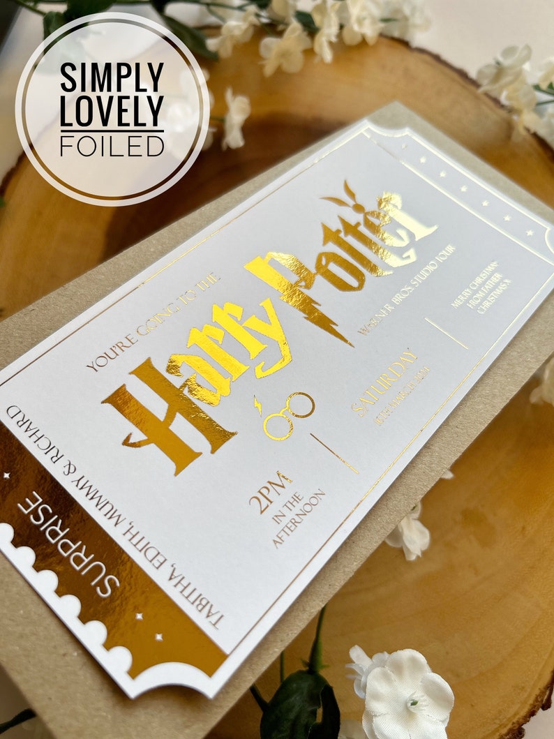 May include: A white ticket with gold foil lettering that reads "You're going to the Harry Potter Warner Bros Studio Tour" and "2PM in the afternoon, Saturday, December 17th, 2022". The ticket has a gold foil border and a gold foil image of Harry Potter's glasses and lightning bolt scar.