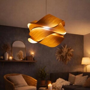May include: A wooden pendant light fixture with a layered, wave-like design. The light fixture is made of warm-toned wood and hangs from a single cord. The light is on, illuminating the room with a soft glow. The fixture is a decorative element.