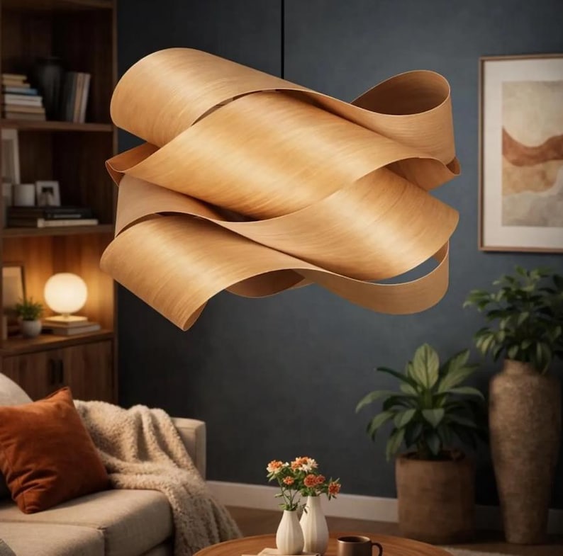 May include: A modern, sculptural pendant light fixture made of layered, light-colored wood. The fixture has a flowing, wave-like design, suspended from the ceiling. The warm wood tones contrast with the dark background, creating a focal point in a living room setting.
