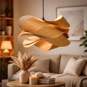 May include: A modern, sculptural pendant light fixture made of layered, light-colored wood. The fixture has a flowing, organic shape with warm, inviting tones. The light is suspended from a black cord, adding a touch of contrast to the natural wood.