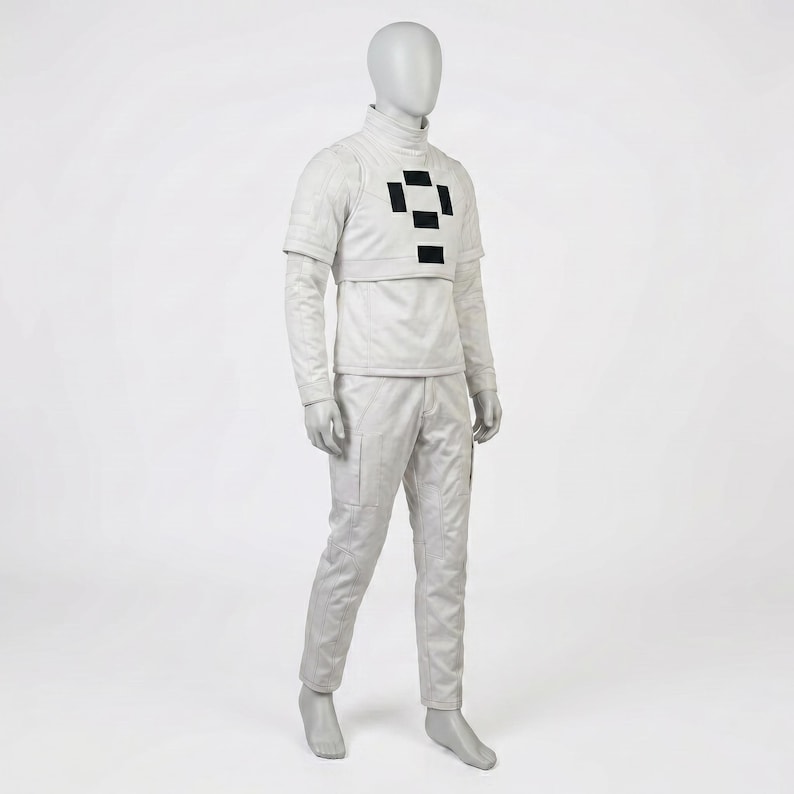 Puede incluir: Un traje futurista gris claro exhibido en un maniqu&iacute;. El atuendo incluye una parte superior de cuello alto con un dise&ntilde;o de cuadrados negros, mangas largas y pantalones a juego. La tela parece texturizada.