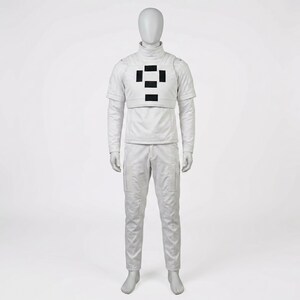 Puede incluir: Un traje blanco completo sobre un maniqu&iacute;. El atuendo incluye una parte superior de manga larga con cuello alto, una pieza en el pecho con detalles rectangulares negros y pantalones a juego con bolsillos de carga. El maniqu&iacute; est&aacute; sobre un fondo blanco.