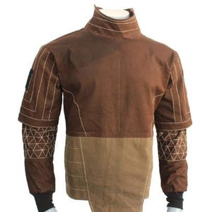 May include: A brown jacket with a high collar and contrasting tan lower section. White stitching details the seams and geometric patterns on the sleeves. The jacket has black cuffs and is displayed on a mannequin.