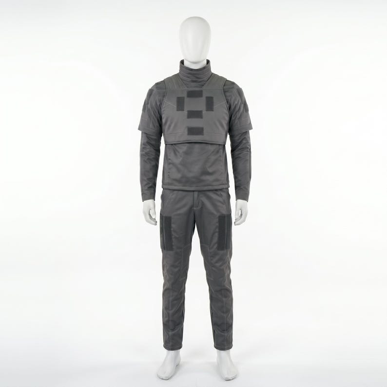 May include: A gray tactical uniform displayed on a mannequin. The outfit includes a high-neck jacket with a chest plate, long sleeves, and matching pants with knee pockets. The uniform is designed for protection and functionality.