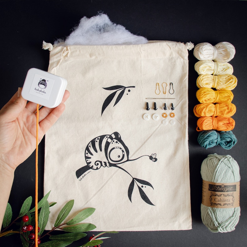 Puede incluir: Un kit de manualidades para hacer un camale&oacute;n de peluche. El kit incluye una bolsa de lona blanca con una ilustraci&oacute;n en blanco y negro de un camale&oacute;n en una rama, una peque&ntilde;a caja de relleno, una aguja, hilo, botones y una variedad de hilos de colores.