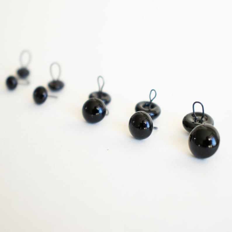 May include: Six black plastic safety eyes with wire loops for attaching to crafts. The eyes are different sizes.