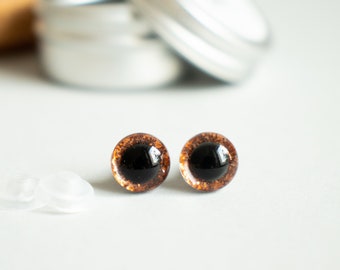 Puede incluir: Dos ojos de seguridad de plástico marrón y negro con acabado brillante. Los ojos tienen un diámetro aproximado de 12 mm.