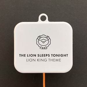 May include: White square music box with a black line drawing of a lion with a crown. The text "The Lion Sleeps Tonight Lion King Theme" is printed on the box.