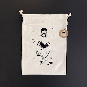 Peut inclure: Un sac en toile blanc à cordon avec une illustration en noir et blanc d'une personne portant un gilet de sauvetage qui se fait avaler par un poisson. Le sac a une étiquette brune avec le texte "babifla.com" dessus.