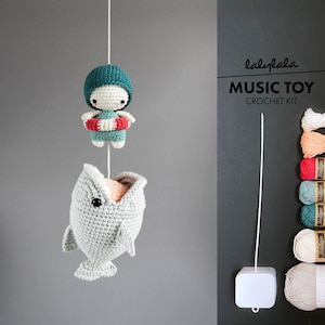 以下が含まれることがあります： 口を開けたクジラ、ライフジャケットを着た小さな編みぐるみ、音楽ボックスが特徴の、かぎ針編み音楽おもちゃキット。キットには、さまざまな色の糸と白い音楽ボックスが含まれています。
