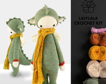 Peut inclure: Deux poupées dragons crochetées à la main, une debout et une accroupie. Les poupées sont vertes avec des écharpes jaunes et des ailes blanches. Le texte "LALYLA CROCHET KIT" est visible sur le côté droit de l'image.