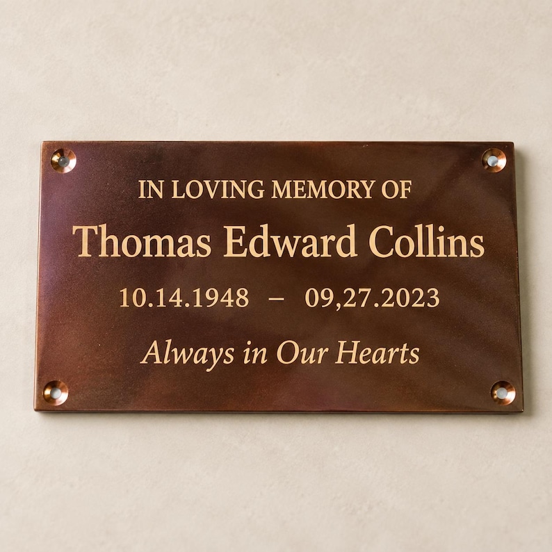 May include: A rectangular bronze memorial plaque with four corner screw holes. The engraved text reads: IN LOVING MEMORY OF Thomas Edward Collins 10.14.1948 &ndash; 09.27.2023 Always in Our Hearts. The metal surface has a polished, dark finish.